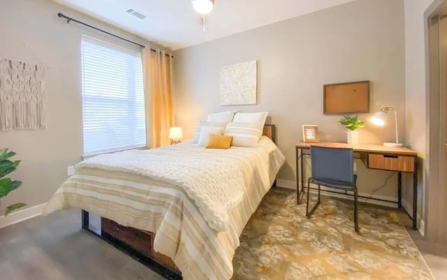 Bed desk chair and rug bedroom at Cedar Pointe Apartments in Blacksburg Student Accommodation