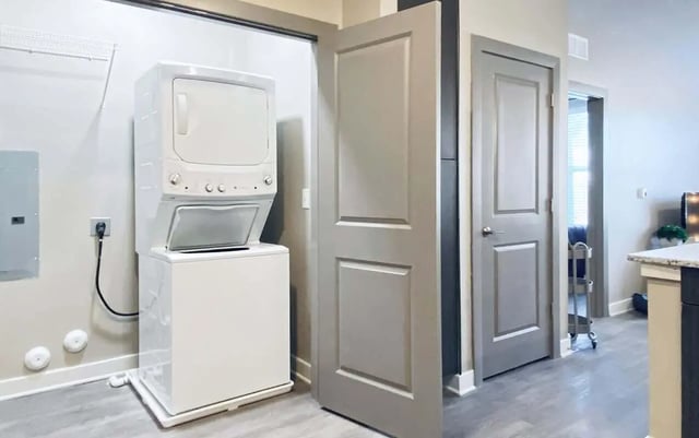 Stacked washer dryer by gray doors laundry area at Cedar Pointe Apartments in Blacksburg Student Accommodation