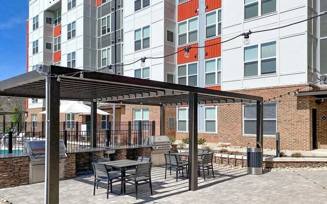 Outdoor kitchen with grills tables chairs and building exterior. at Cedar Pointe Apartments in Blacksburg Student Accommodation