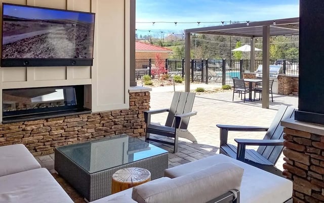 Outdoor patio furniture fireplace television pool area at Cedar Pointe Apartments in Blacksburg Student Accommodation
