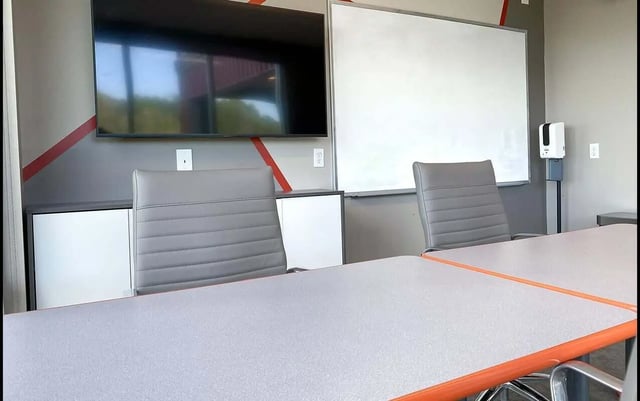 Conference table with chairs and whiteboard meeting room at Cedar Pointe Apartments in Blacksburg Student Accommodation