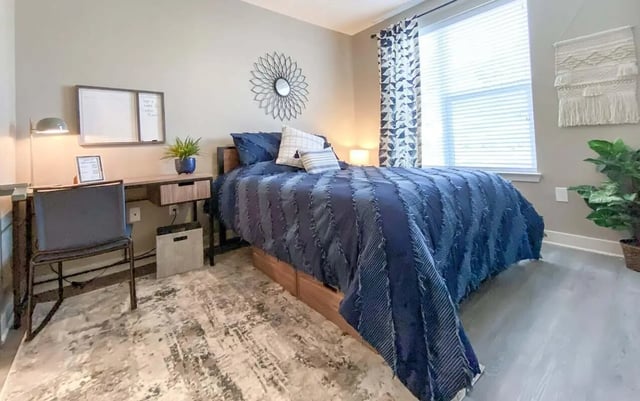 Bed desk chair whiteboard and plant bedroom at Cedar Pointe Apartments in Blacksburg Student Accommodation