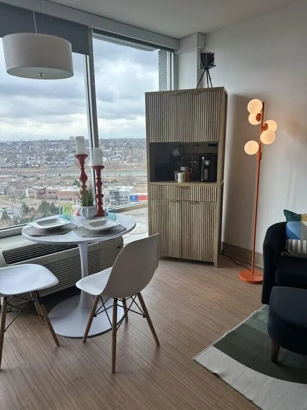 Dining table chairs cabinet and floor lamp living room at Assembly Student Living in Denver Student Accommodation