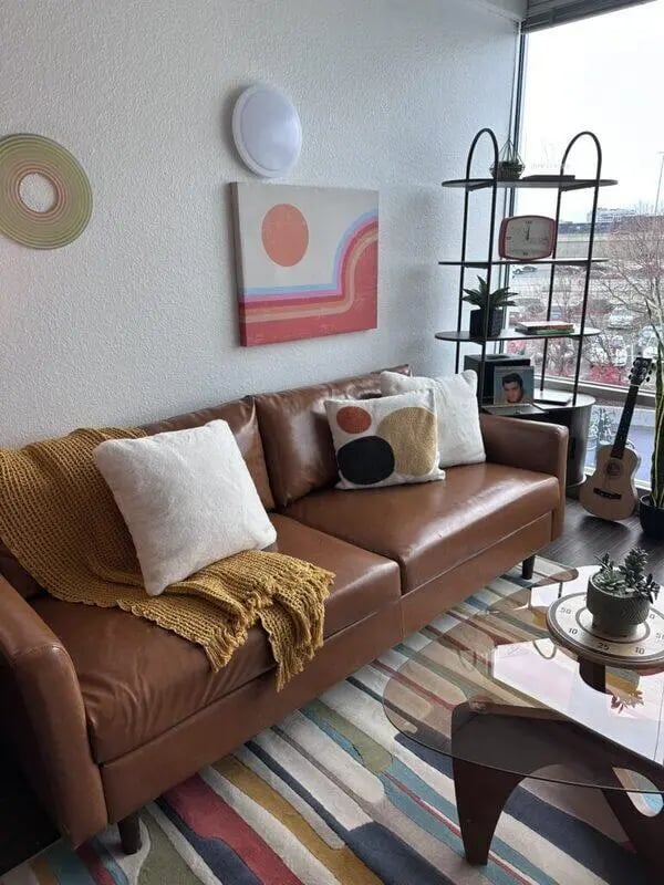 Brown leather sofa colorful rug artwork living room at Assembly Student Living in Denver Student Accommodation