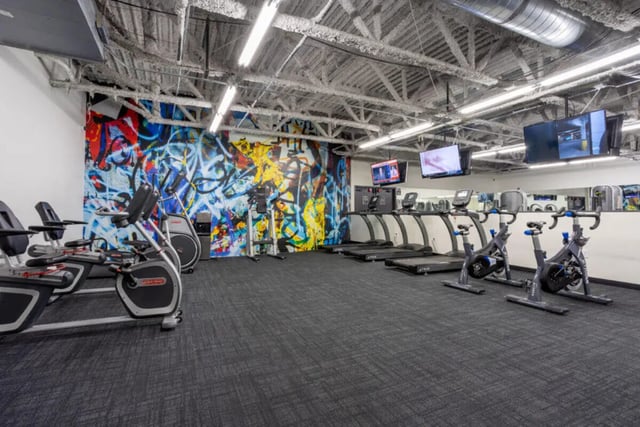 Treadmills stationary bikes with graffiti wall gym at Assembly Student Living in Denver Student Accommodation