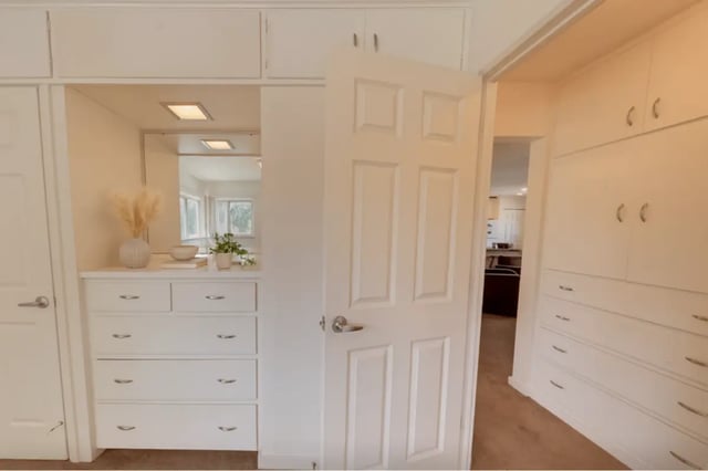 White dresser with mirror and plants bedroom at Cedar Street Apartments in East Lansing Student Accommodation