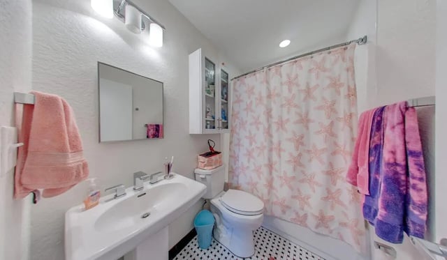 Sink toilet cabinet shower curtain bathroom at Deco '39 Luxury Apartments in Gainesville Student Accommodation