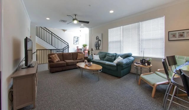 Sofas coffee table TV stairs living room at Deco '39 Luxury Apartments in Gainesville Student Accommodation