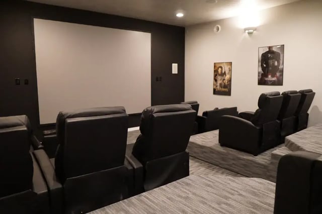 Black recliners movie posters large screen theater room at Pinnacle Point Apartments in Rexburg Student Accommodation