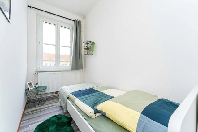 Bed with green blue quilt and side table bedroom at Sterndamm 83.4 in Berlin Student Accommodation