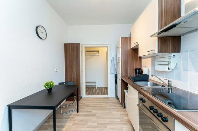 Table chairs sink cabinets stove clock kitchen at Sterndamm 83.4 in Berlin Student Accommodation