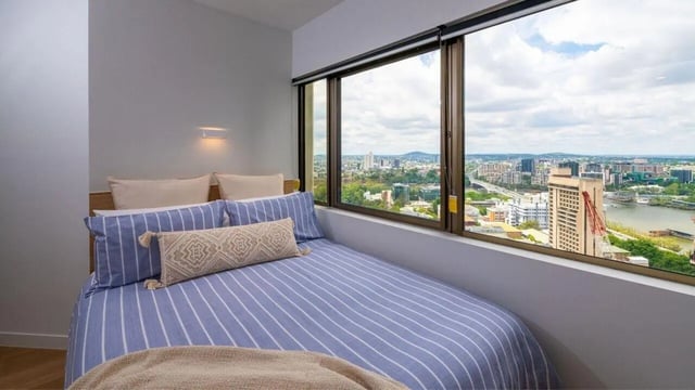 Bed with striped duvet and city view bedroom at UniLodge Brisbane City in Brisbane Student Accommodation