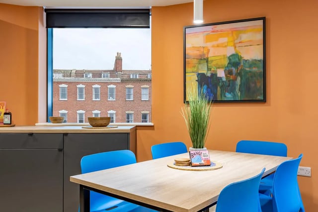 Dining table blue chairs artwork and kitchen area at Croft Court in Bristol Student Accommodation