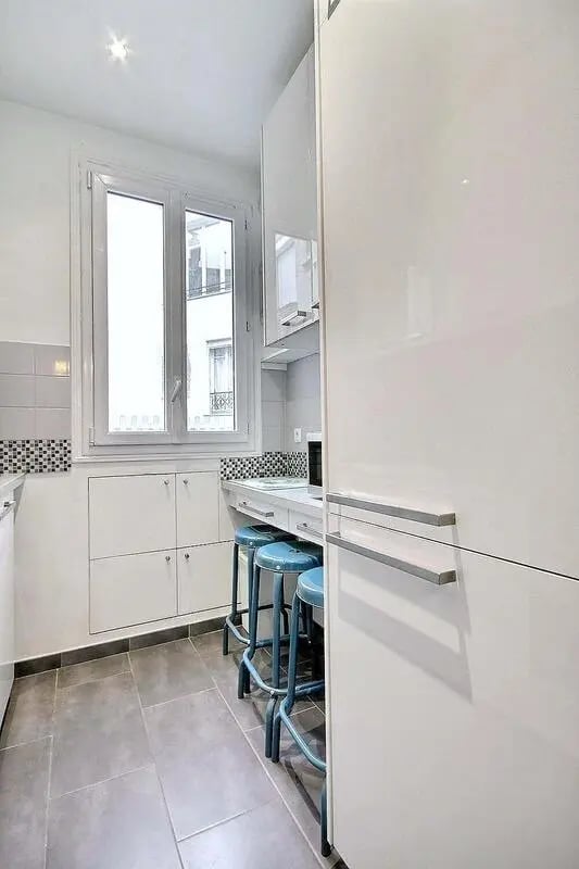 Blue stools by white counter window kitchen at Apartment in Rue Damrémont, 75018 Paris, France in Paris Student Accommodation