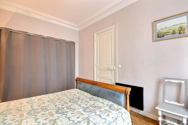 Bed with patterned duvet grey curtains open door Bedroom at Apartment in Rue Damrémont, 75018 Paris, France in Paris Student Accommodation