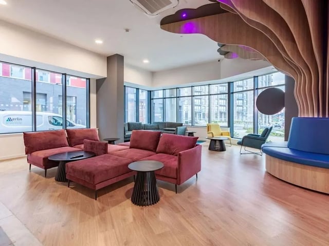 Burgundy sectional sofas with black tables common area at Pavilion Court London in Wembley Student Accommodation