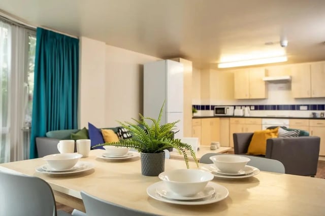 Dining table with place settings and kitchen living area. at Burley Road in Leeds Student Accommodation