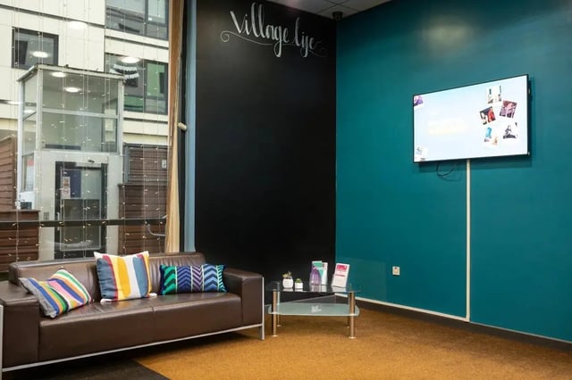 Brown sofa colorful pillows glass coffee table lounge area at Burley Road in Leeds Student Accommodation