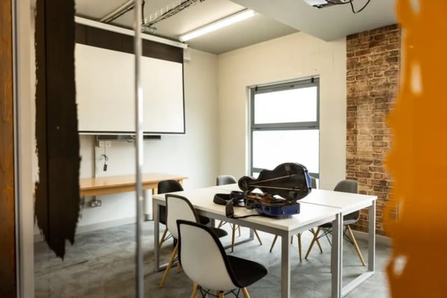 Table chairs projector screen and violin case meeting room at Mcmillan student Village in Greenwich Student Accommodation
