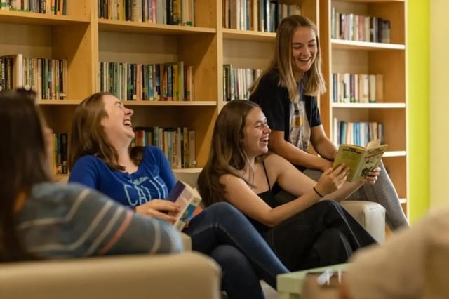 Students laughing with books by bookshelves common area at Bonington Student Village in Loughborough Student Accommodation