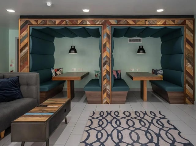 Two teal booths with tables and a sofa living room at Meadow Court in Edinburgh Student Accommodation