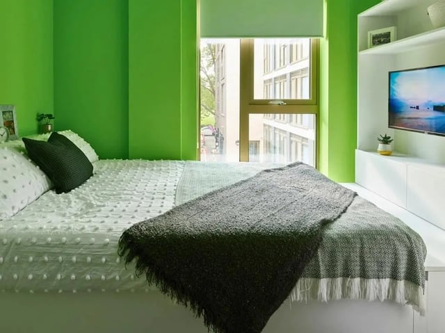 Bed with pillows throw blanket TV shelf Bedroom at View Studios in London Student Accommodation