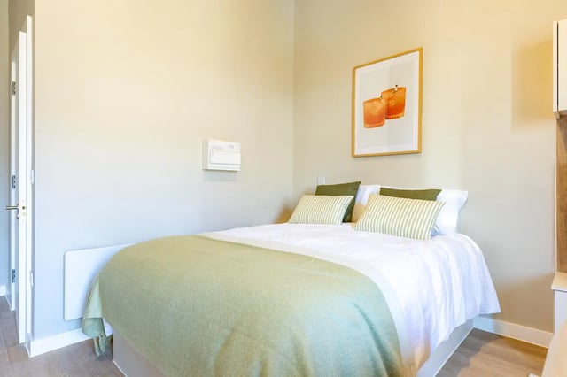 Bed with green blanket artwork and pillows bedroom at Fitz and Knox in Cardiff Student Accommodation