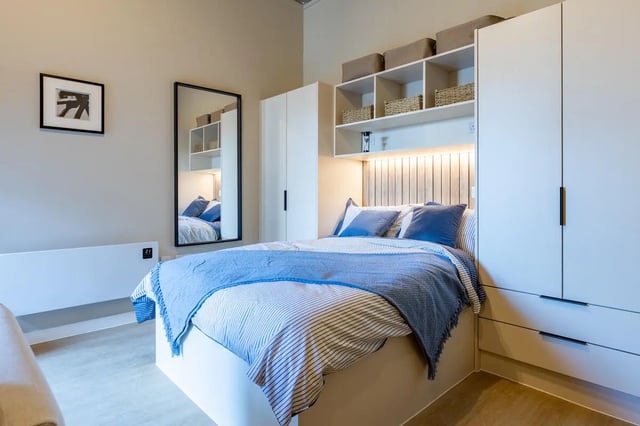Bed with blue throws bedside mirror shelving bedroom at Fitz and Knox in Cardiff Student Accommodation
