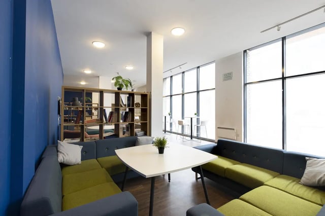 Blue and green sofas white table bookshelves plants common area at Marshall Court in Newcastle Upon Tyne Student Accommodation