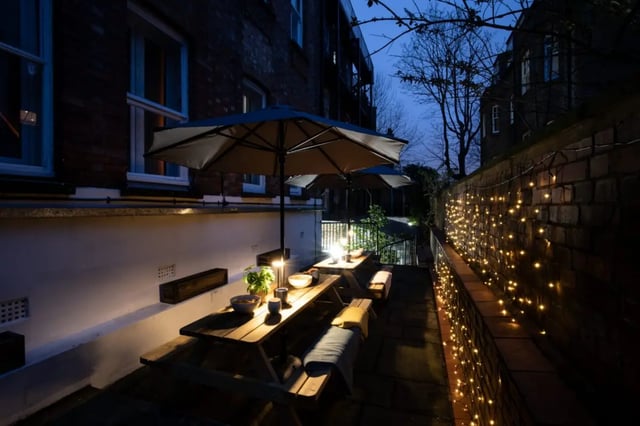 Picnic tables with umbrellas and string lights exterior at Francis Gardner in London Student Accommodation