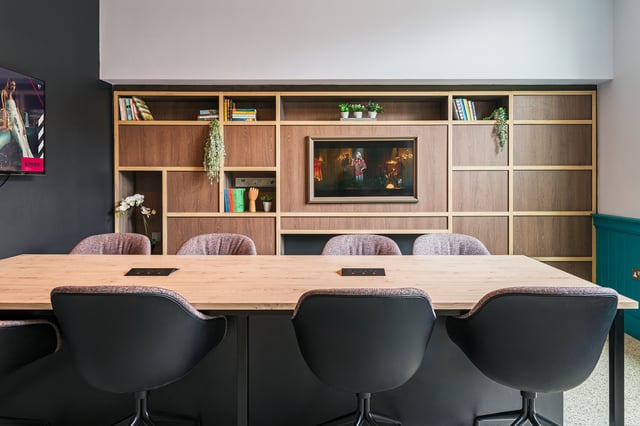 Wood table chairs built-in shelves with television common area at Vita Student Zed Alley in Bristol Student Accommodation