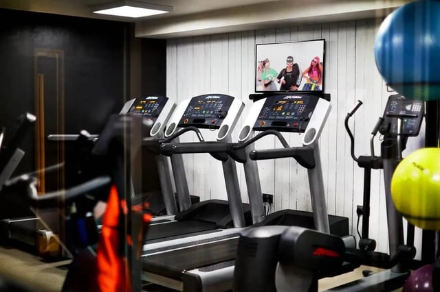 Treadmills and elliptical with a screen playing Image Type at Vita Student Telephone House - Sheffield in Sheffield Student Accommodation