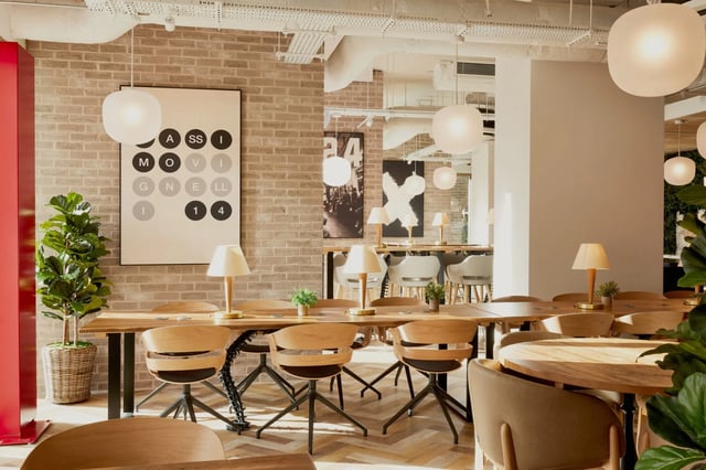 Wooden tables chairs and lamps communal area at Vita Student Lewisham Exchange in London Student Accommodation