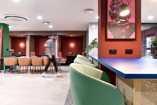 Modern communal area with tables chairs and artwork. at Vita Student Iona Street in Edinburgh Student Accommodation