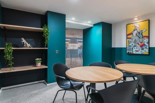 Round tables black chairs plant decor and art lounge area at Vita Student Portland House - Exeter in Exeter Student Accommodation