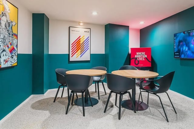 Four round tables black chairs poster artwork living room at Vita Student Portland House - Exeter in Exeter Student Accommodation