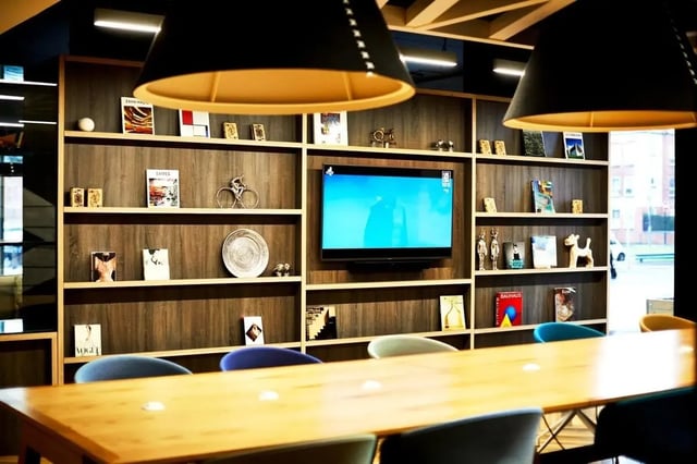 Bookshelf with TV and dining table communal area at Vita Student West End - Glasgow in Glasgow Student Accommodation