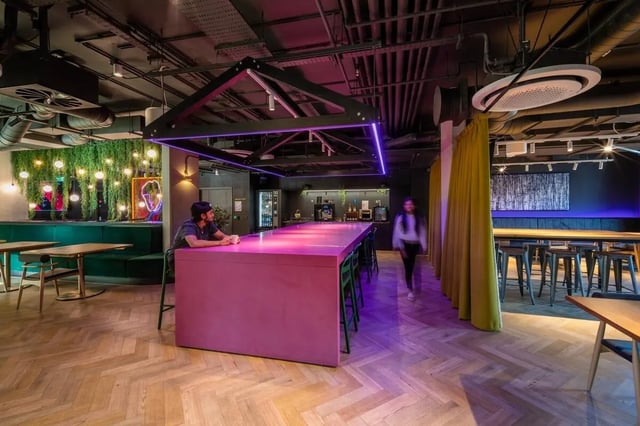Pink island counter green booths neon lights communal area at Vita Student Park Place in Cardiff Student Accommodation