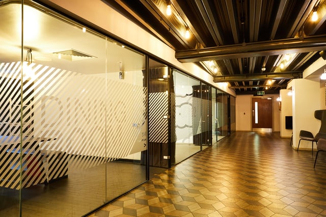 Glass walled offices with desks and patterned floor corridor at Vita Student Crosshall Street in Liverpool Student Accommodation