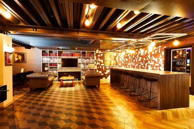 Leather sofas fireplace bookshelves long bar stools living area at Vita Student Crosshall Street in Liverpool Student Accommodation
