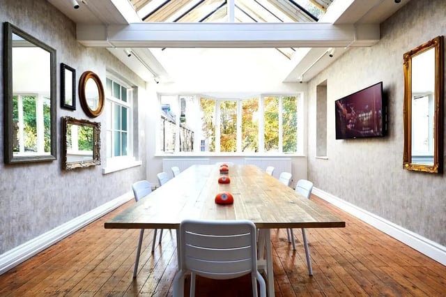 Long wooden table with orange call buttons and chairs communal area at Vita Student Lawrence Street in York Student Accommodation