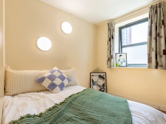 Bed with pillows and green blanket bedroom at Europa in Liverpool Student Accommodation