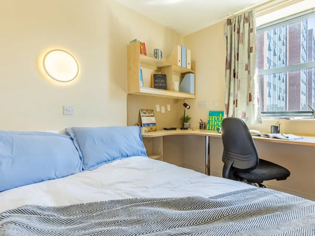 Bed with blue pillows desk shelves chair bedroom at Europa in Liverpool Student Accommodation