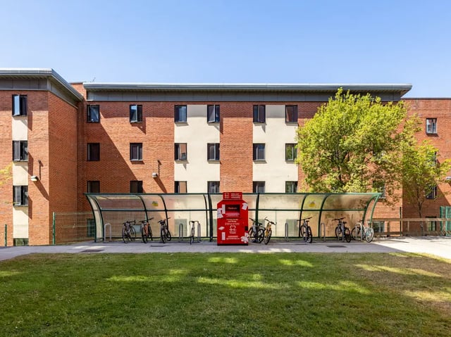 Bikes under shelter with red donation bin exterior at Europa in Liverpool Student Accommodation