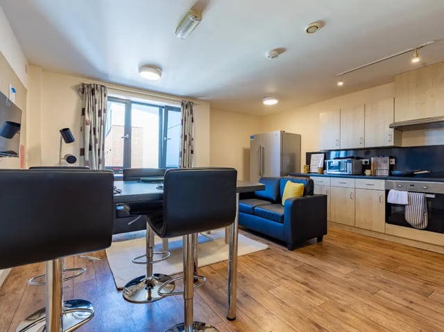 Table with bar stools sofa and kitchen living room at Europa in Liverpool Student Accommodation