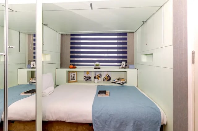 Bed with blue throw and shelf decorations bedroom at The Stay Club - Kentish Town in London Student Accommodation