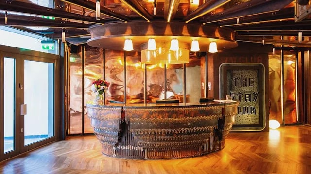 Ornate reception desk with flowers and a sign Reception area at The Stay Club - Kentish Town in London Student Accommodation