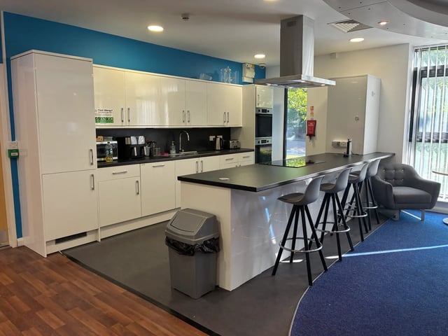 Modern white kitchen island with bar stools and sofa kitchen at Newport Student Village in Newport Student Accommodation