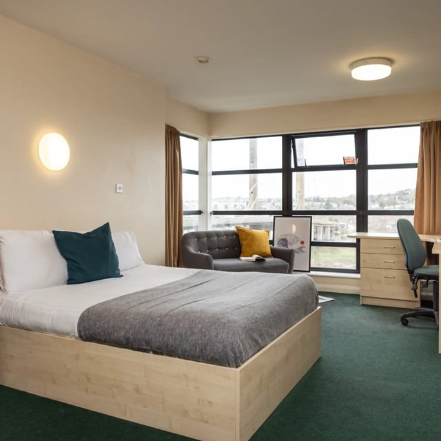 Bed with grey throw desk chair and large window bedroom at Newport Student Village in Newport Student Accommodation