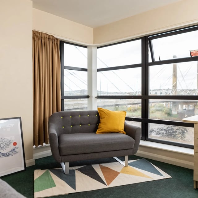 Grey sofa yellow cushion rug living room at Newport Student Village in Newport Student Accommodation